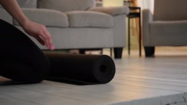 Kadın apartman dairesinde yoga minderi hazırlıyor.