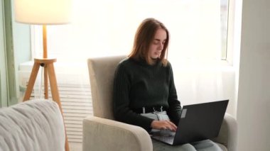 Evde dizüstü bilgisayar kullanan bir kadın.