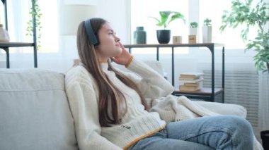 Kaygısız kadın kanepeye uzanıp müzik dinliyor.