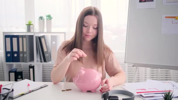 Молода жінка вручає гроші в скарбничку — стокове відео