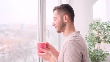 Yakışıklı adam kahve içiyor ve pencereye bakıyor.
