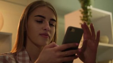 Kanepede oturan ve akıllı telefon kullanan güzel bir kadın.