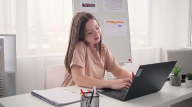 Kadın evde çalışıyor ve bilgisayarda yazarken telefonla konuşuyor.