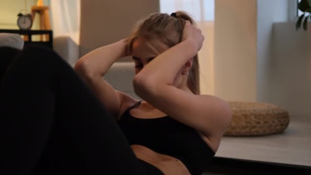 Νεαρή γυναίκα κάνει ασκήσεις κοιλιακών στο πάτωμα — Αρχείο Βίντεο