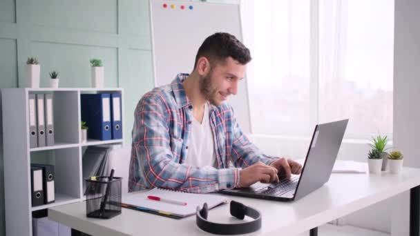 Молодой человек работает в домашнем офисе, используя ноутбук — стоковое видео