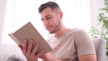 Genç adam kanepede oturup kitap okuyor.