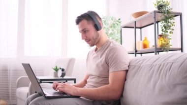 Adam evden kanepeye oturup müzik dinliyor.