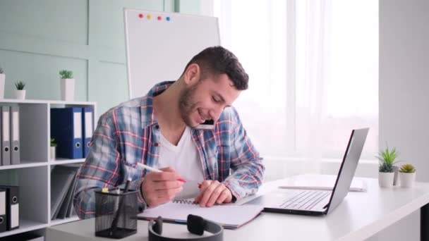 Student sitting at working place, working on laptop computer, talking phone — Stock Video