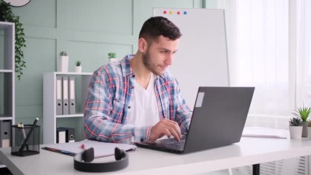 Кавказский мужчина и курящий, работающий в домашнем офисе, используя ноутбук — стоковое видео
