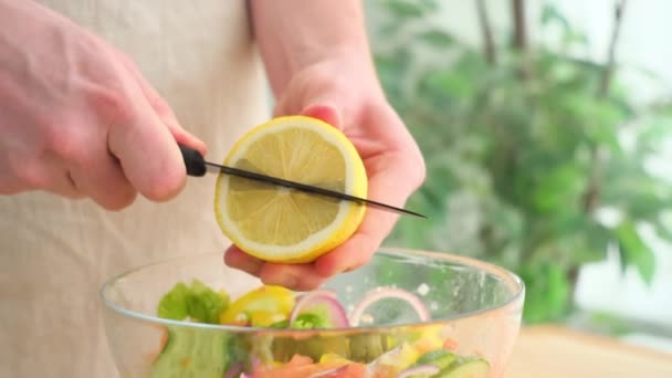 L'homme presse le jus de citron dans un bol avec salade — Video
