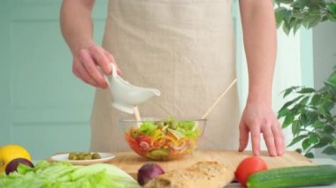 Adam taze sebze salatasına zeytin yağı döküyor.