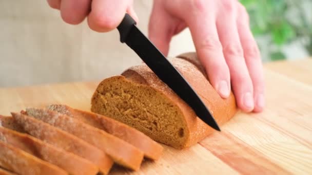 Man skär bröd på träskiva — Stockvideo