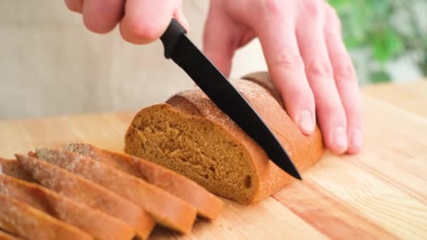 Homme coupant du pain sur planche de bois — Video