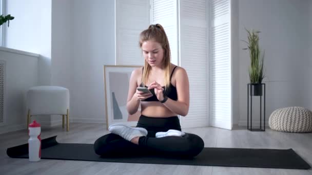 Frau hält Smartphone nach dem Training entspannt in der Hand — Stockvideo