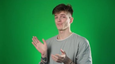 Sarı tişörtlü sıkılan adam yeşil arka planda el çırpıyor.