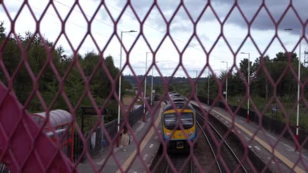 Tren espera en la estación de tren vista a través de valla — Vídeos de Stock