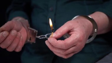 Elleri kelepçeli kibrit çakıyor