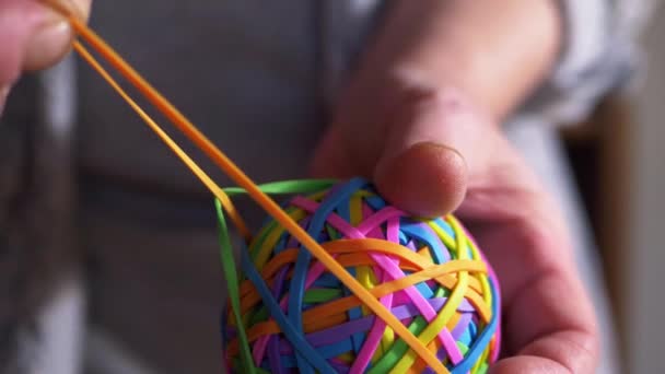 Hand stretching rubber band on colorful ball — Stock Video