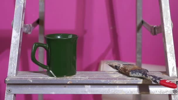 Mok koffie en verfborstel op metalen trapladders — Stockvideo