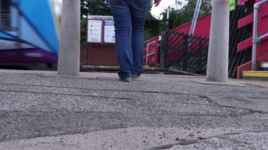 Banliyö, tren istasyonundan geçen trene doğru yürüyor.