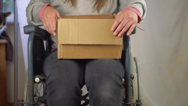 Utilisateur de fauteuil roulant ouvrant une boîte en carton — Video