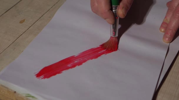 Verfkwast streelt rode verf op papier — Stockvideo