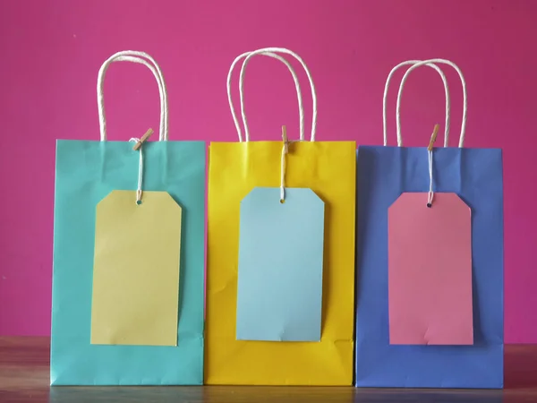 Fila de bolsas de regalo y etiquetas sobre fondo rosa — Foto de Stock