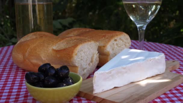 Brie és olívabogyó a piknik asztalon, dalmás napfényben — Stock videók