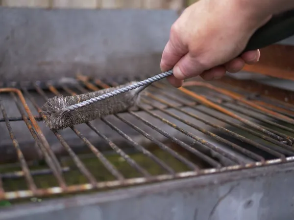 Cleaning dirty bbq grill with brush wide shot