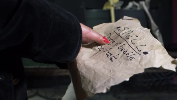 Häxan läser en trollformel på pergamentpapper. — Stockvideo