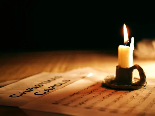 Christmas carols music song sheet with candle — Stock Photo, Image