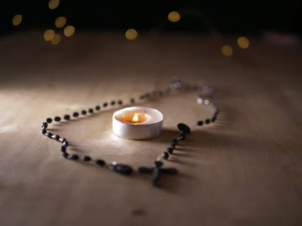 Einsame Teelichterkerze mit Rosenkranz-Perlen — Stockfoto