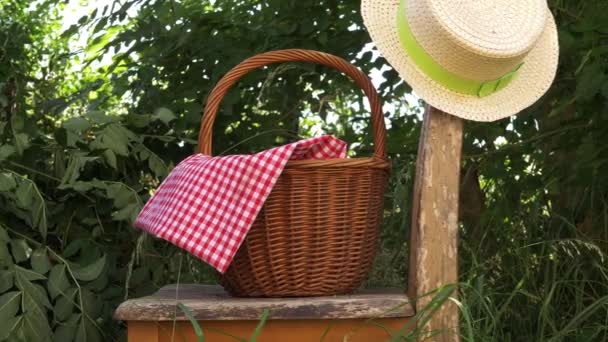 Cesta de picnic con sombrero de paja en silla de jardín rickety — Vídeos de Stock