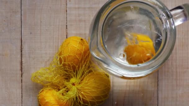 Kapání čerstvých citronů do džbánu s vodou — Stock video
