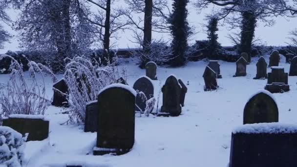Church graveyard in winter as snow is falling — Stock Video