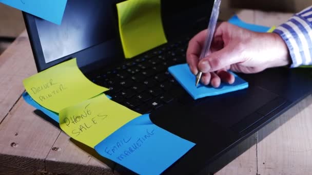 Busy worker writing notes and memos on laptop — Stock Video