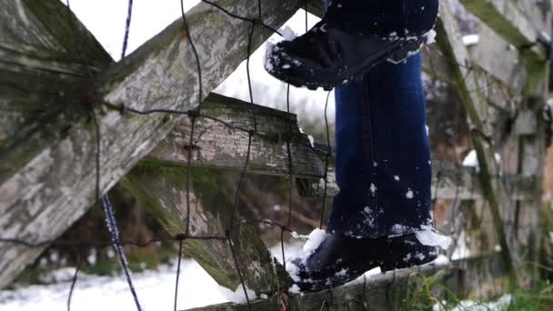 Wanderer erklimmt klappriges Holztor im Winterschnee — Stockvideo