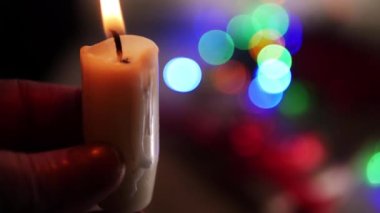 Bir mum tutuyorum Noel ışıkları arka planda. 