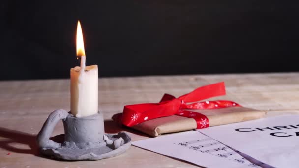 Weihnachtsliederblatt mit Kerze und Geschenk — Stockvideo
