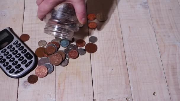 Hands tipping coins out of a savings jar — 图库视频影像