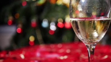 Bir kadeh beyaz şarap ve arka planda Noel ışıkları. 