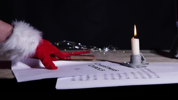 Χέρι κρατώντας τα κάλαντα χριστουγεννιάτικο φύλλο μουσικής από το φως των κεριών — Αρχείο Βίντεο