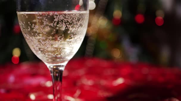 Glass of white wine on table with Christmas bokeh lights background — Vídeo de Stock