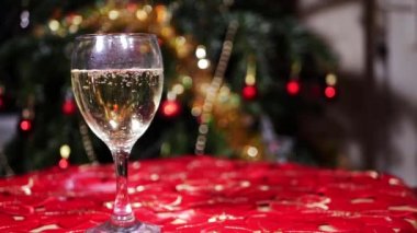 Bir kadeh beyaz şarap ve arka planda Noel ışıkları. 