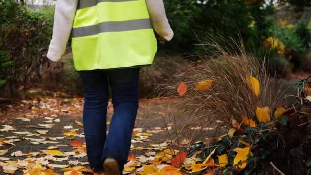 Park attendant worker walks through public park in Autumn — Stockvideo