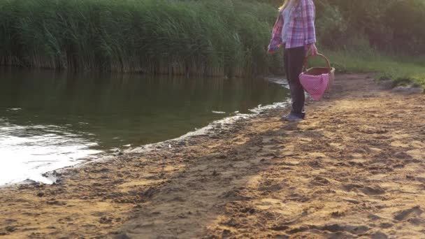 Vrouw staat aan meerzijde met vintage picknickmand — Stockvideo