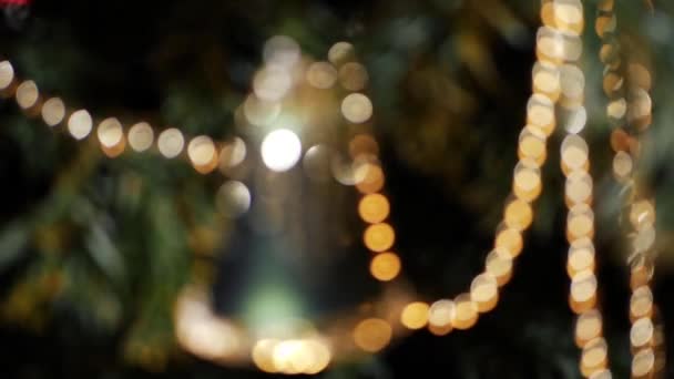 Christmas bell decoration hangs on the tree golden and green bokeh defocussed — Stockvideo