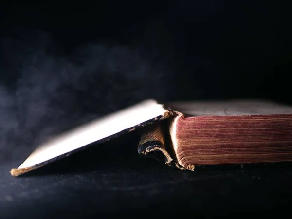 Vecchio libro consumato su sfondo scuro fumo — Foto Stock