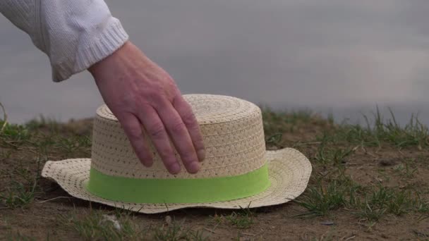 Kobieta podnosi słomkowy kapelusz na piasku. — Wideo stockowe