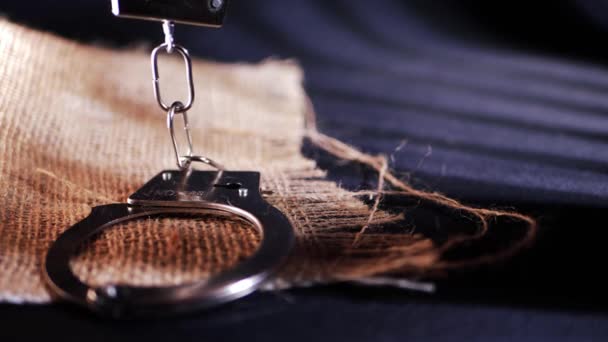 Handcuffs in prison shadows on sackcloth background — Stock video